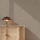 Minimalist room with light ivory vertical lines wallpaper, dark brown sideboard, black decor, and leafy branch arrangement.