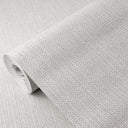 White raffia texture wallpaper featuring a small-scale grid of raised squares and interlocking threads. This natural-fiber inspired design provides a tactile, hand-woven quality, ideal for coastal or casual interiors. Made in the USA with eco-friendly materials.