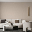 Warm beige plaster wallpaper with a delicate vertical sheen, alternating shadowed recesses and gently raised texture for quiet depth. Irregular patches of denser grain add tactile interest without overt pattern, suited to refined modern interiors. Requires adhesive.