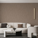 Close-up of textured brown plaster wallpaper, featuring vertical ridging and a luminous effect, suitable for adding depth to any room without overpowering furnishings.