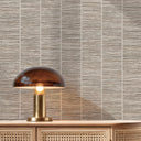 Close-up view of sand beige grasscloth wallpaper with a tightly woven pattern and faint vertical striations. The fibrous texture adds a natural, layered look to hospitality corridors or cozy bedrooms. This wallpaper, made in the USA, enhances interior design with its subtle color variations and tactile surface. Requires wallpaper adhesive.