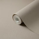 A roll of textured neutral beige wallpaper, partially unrolled to show its matte beige surface, set against a matching beige background.